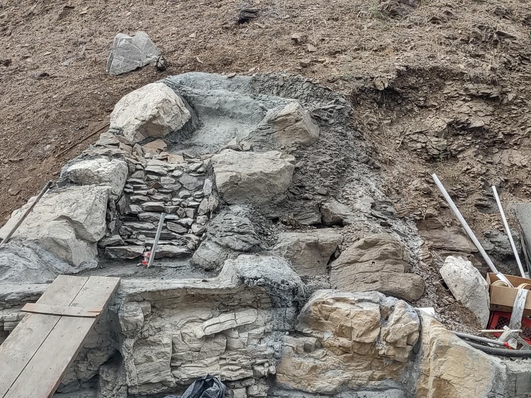 Construction site with stone steps and rocky terrain, showcasing building materials and tools.
