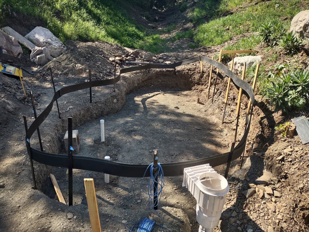 Excavated area with framing for foundation and plumbing in a construction site.