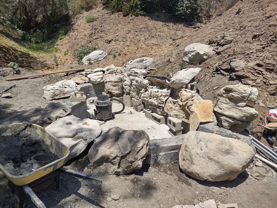 Stone landscaping in progress, featuring rock formations and construction materials.