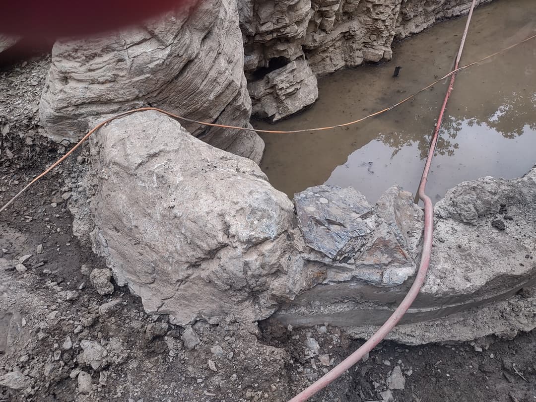 Rocky landscape with water and exposed geological formations in an excavation site.