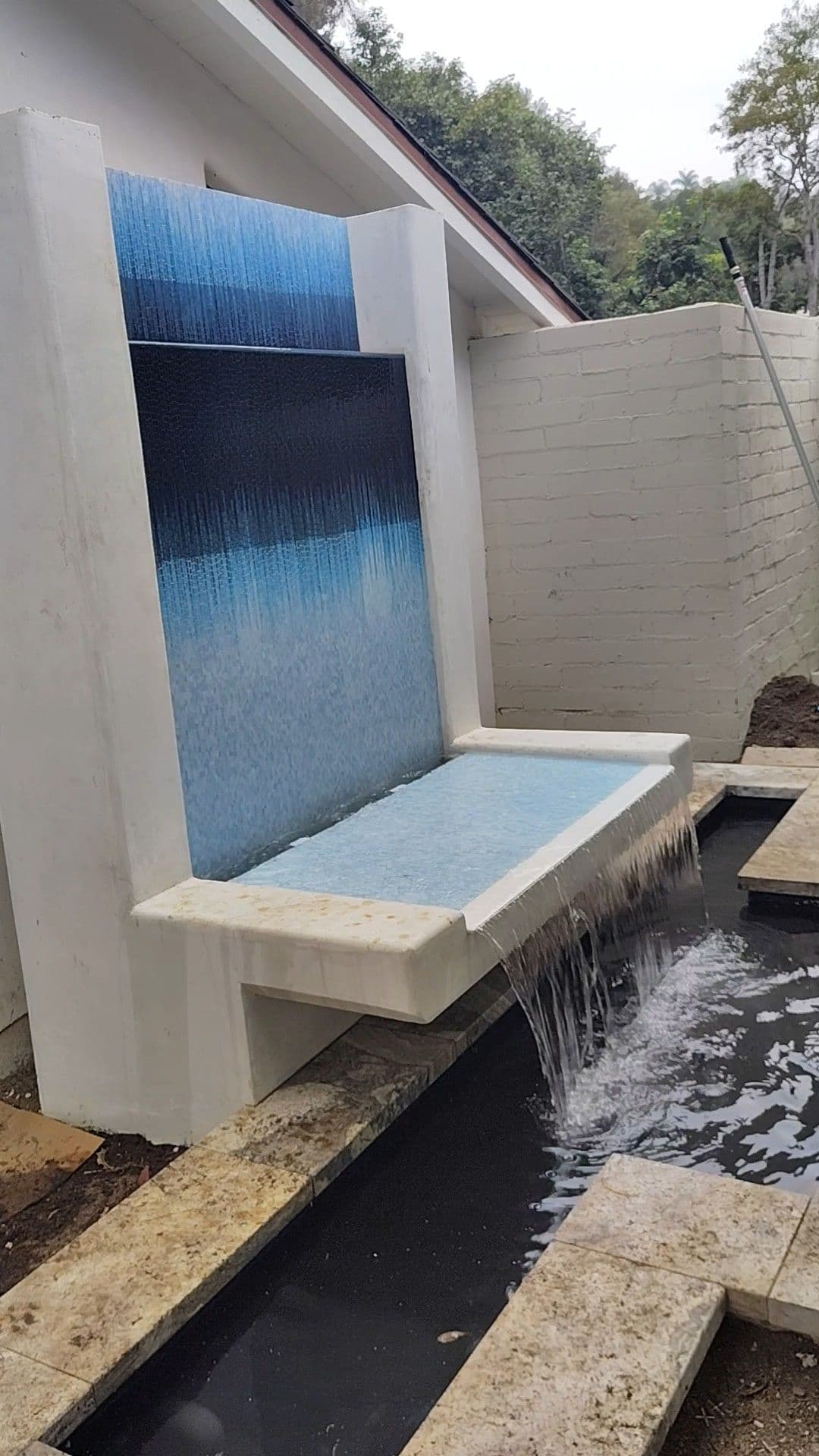Modern outdoor water feature with cascading water and colorful tile design.